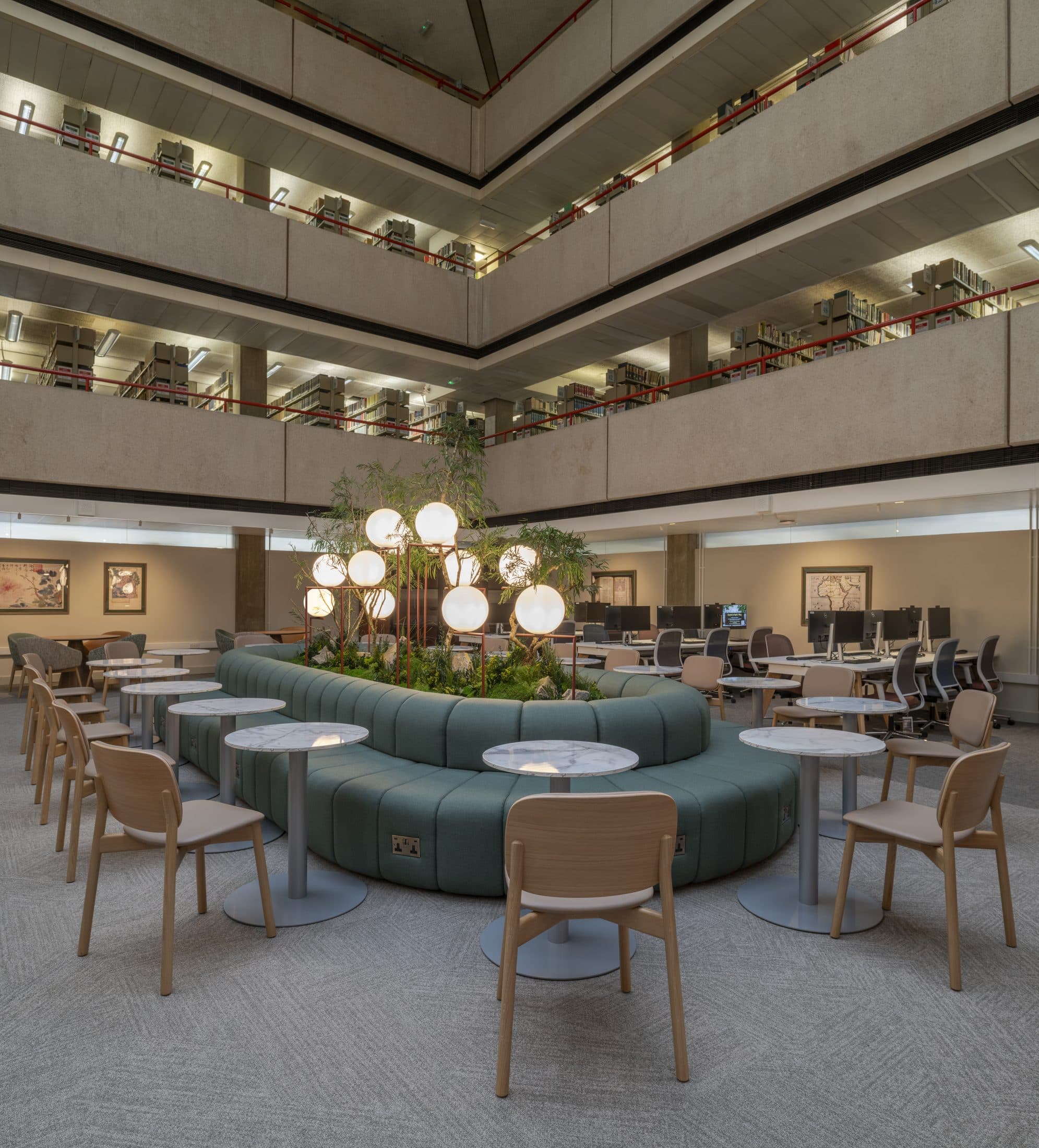 Curved green banquette built around a central planter in a multi-storey office atrium