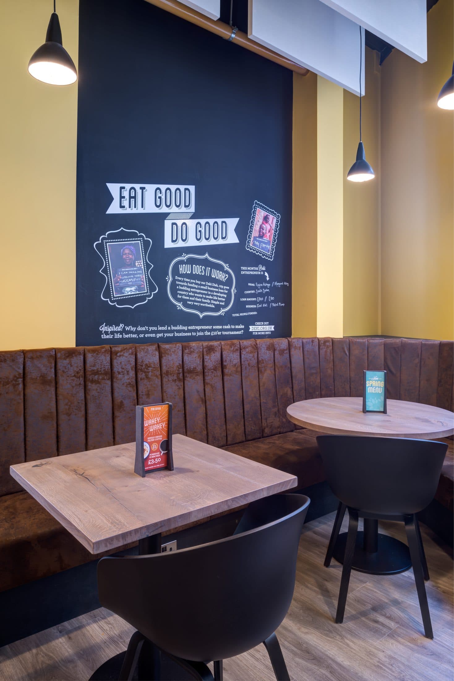 Fluted brown leather corner banquette with oak café tables under pendant lights